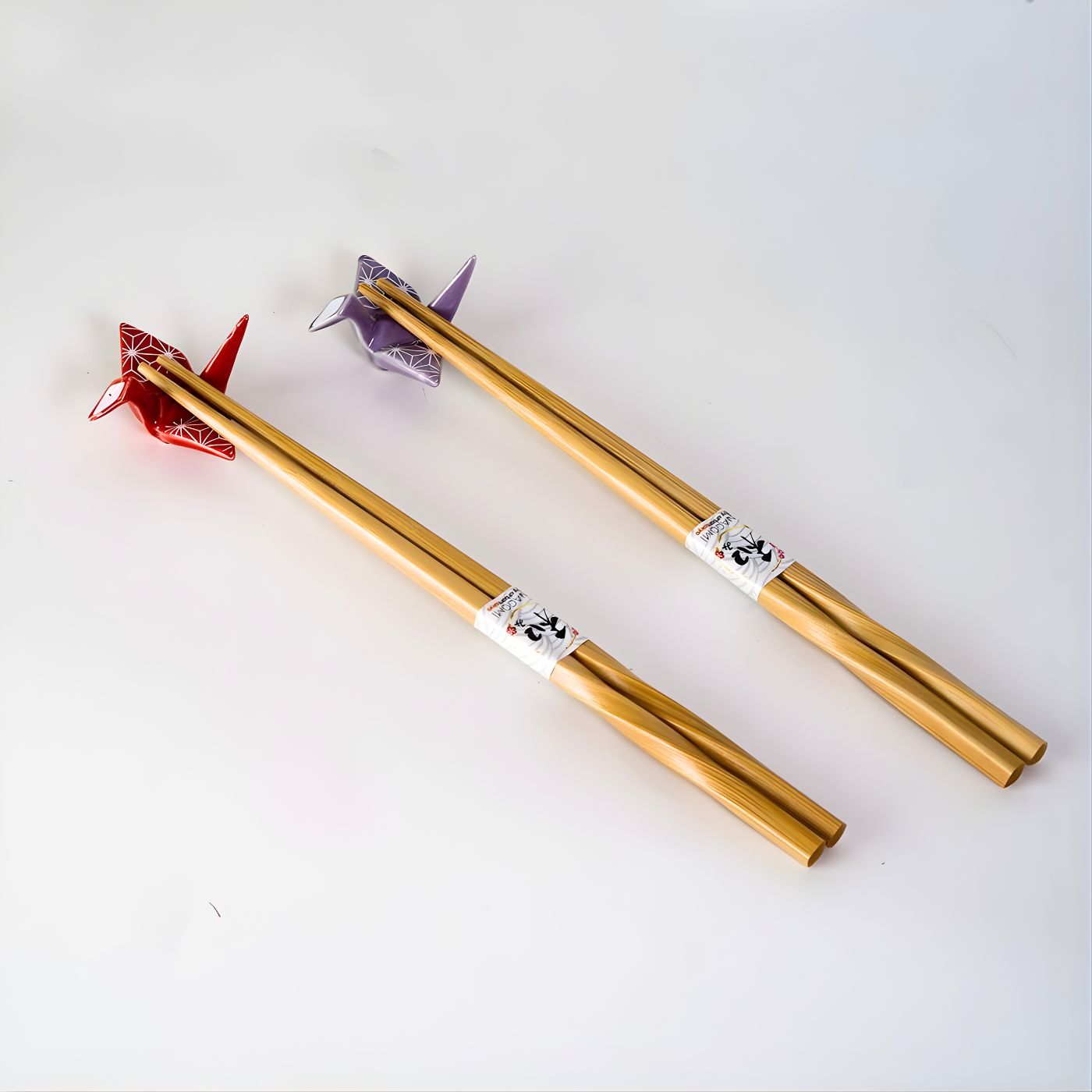 Bamboo chopsticks with smooth twisted design for balanced grip on ceramic chopstick rest shaped like origami crane in red and purple