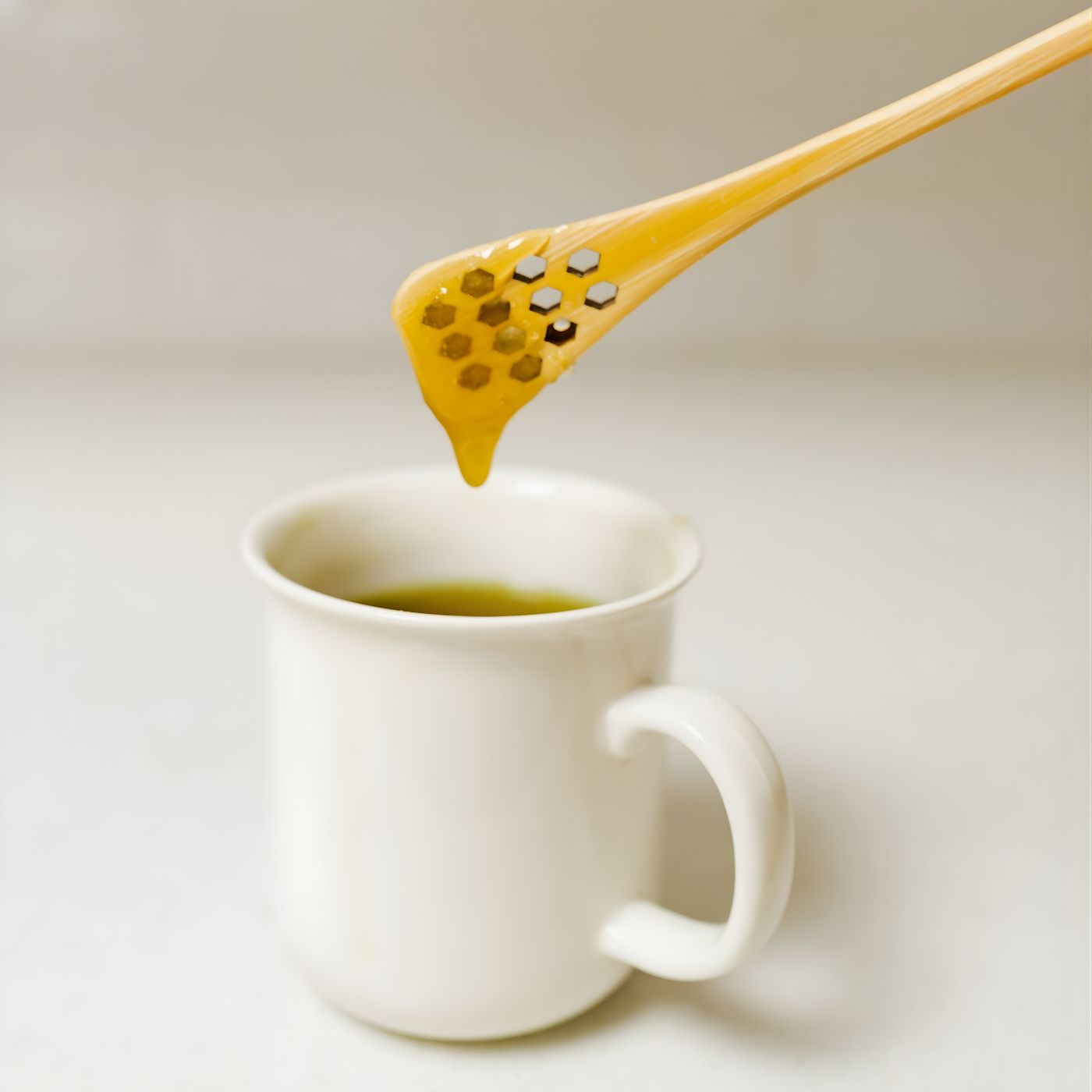 Honey spoon drizzling honey into cup