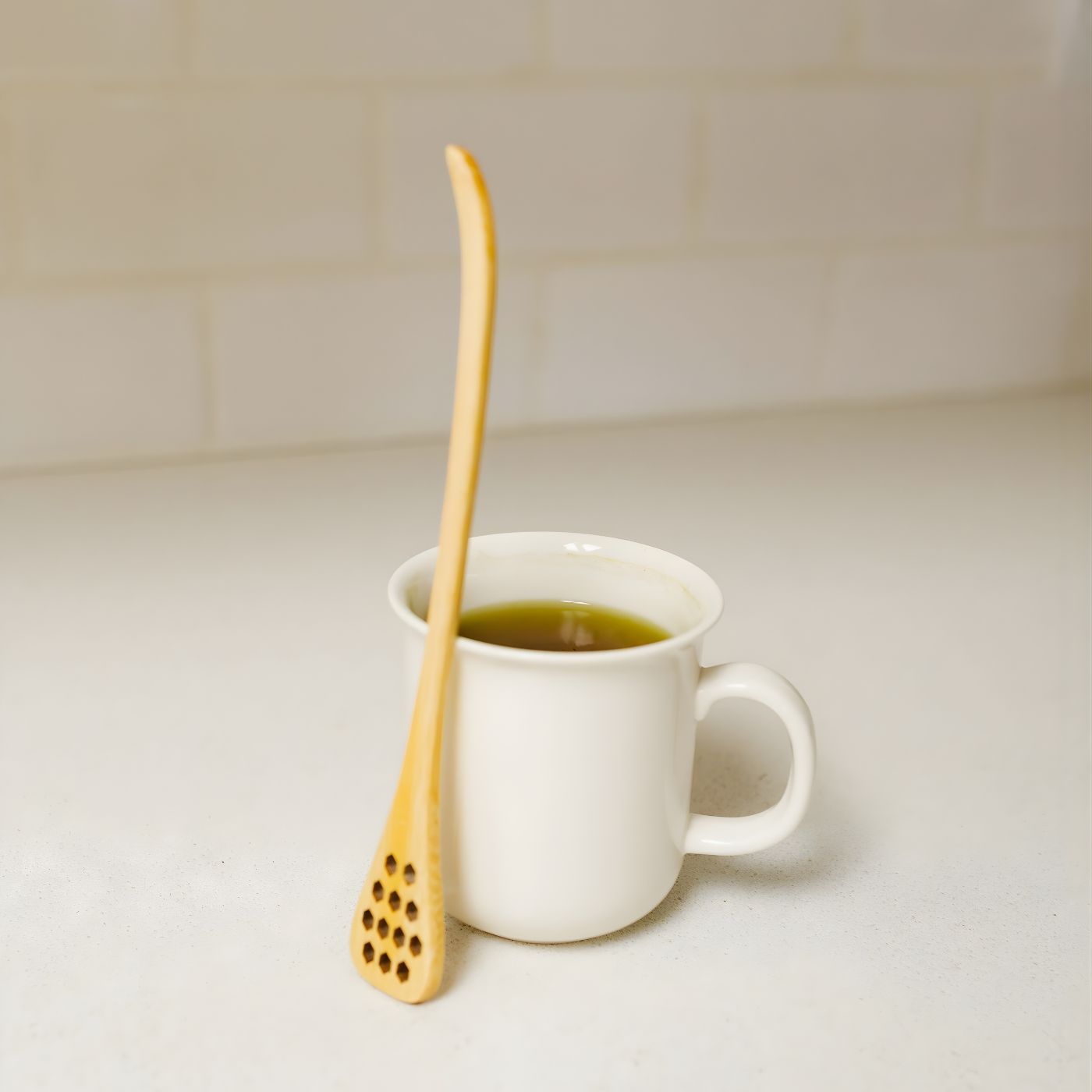 Bamboo honey dipper next to cup of tea