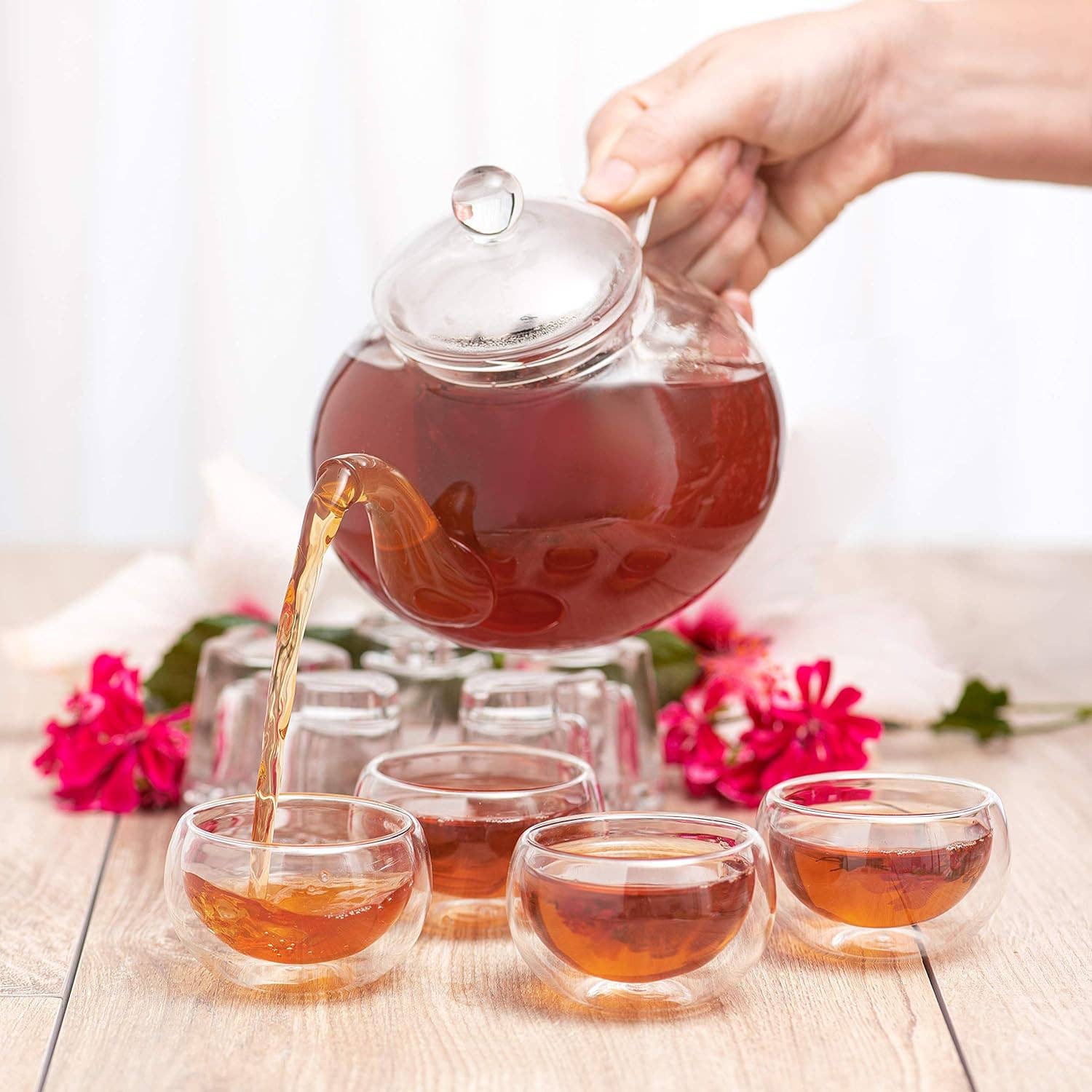 Pouring tea from glass tea kettle into cups