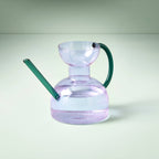 Clear glass purple watering can with water