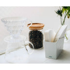 White porcelain V60 filter stand beside coffee dripper and server