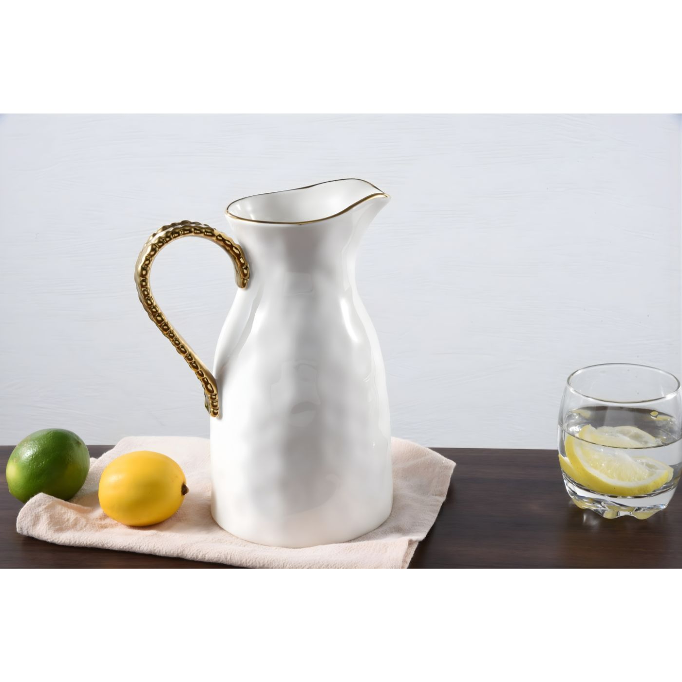 White porcelain water pitcher on dining table with glass of lemon infused water