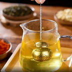Teapot tea infuser steeping in glass tea cup