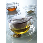 Loose leaf tea steeping in glass cup with steel strainer