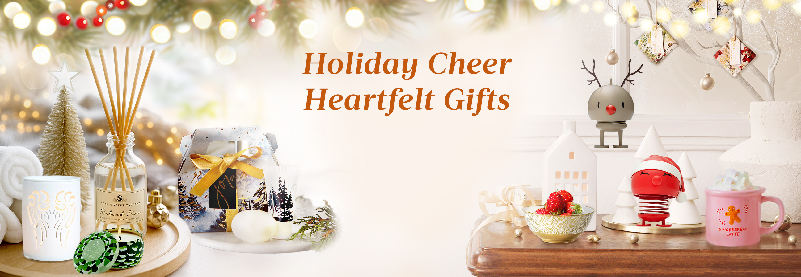 Festive Christmas gift display with candles, aroma diffuser, holiday decorations, and warm golden bokeh lights.