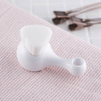 Kai High Density Facial Cleansing Brush with soft white bristles resting on a towel for skincare use.