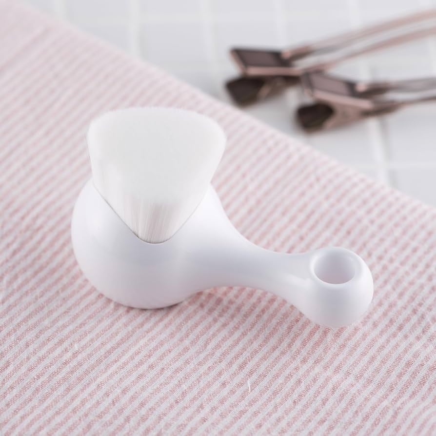 Kai High Density Facial Cleansing Brush with soft white bristles resting on a towel for skincare use.